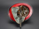 an old red and black helmet with a metal buckle on the side