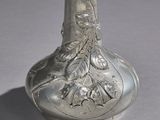 a silver vase with a design on it on a table