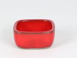 a small red bowl sitting on a white surface