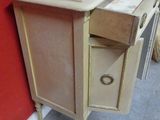 a small table with a drawer on it next to a red wall