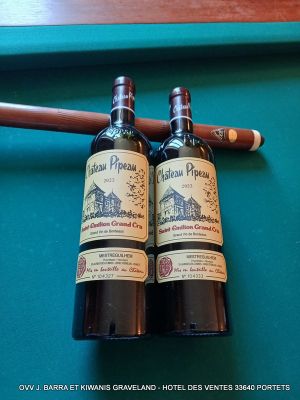 deux bouteilles de vin et un cigare posés sur une table de billard