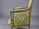 an antique chair with a green upholstered back and gold trim