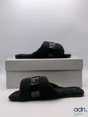 black sued slippers with buckles and a box on a white surface