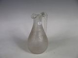 a glass vase with a chain around it on a white surface