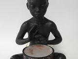 figurine of a boy sitting on the ground with a bowl in his hands