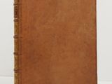 an old book with a brown cover sitting on top of a white table