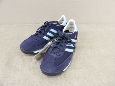 une paire de baskets Adidas bleues posées sur une surface beige