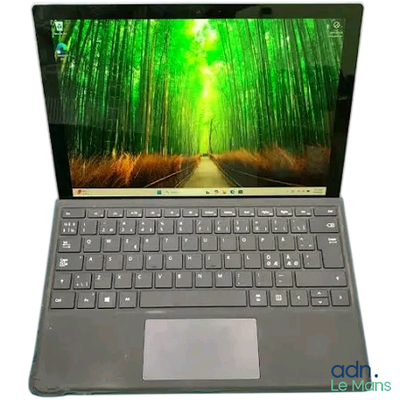 l'ordinateur portable est ouvert sur une surface blanche, avec des arbres verts en arrière-plan