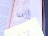 un livre ouvert sur lequel se trouve une feuille de papier