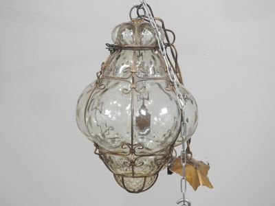 une lanterne en verre suspendue au plafond par une chaîne