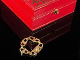 a small red box with a gold brooch on it