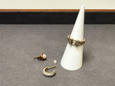un cône blanc orné d'un anneau, à côté d'une paire de boucles d'oreilles et d'une autre paire de boucles d'oreilles