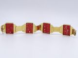 pair of red and gold cuff bracelets on a white surface