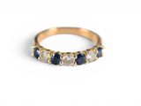 gros plan d'une bague en or avec des pierres bleues et blanches