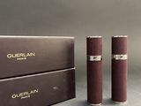 pair of burgundy colored lipsticks sitting next to a box of perfume