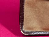 an image of a brown and tan purse on a pink surface