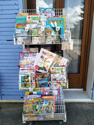 un chariot chargé de magazines devant un magasin