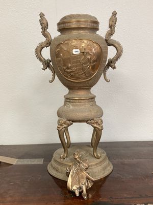une urne en bronze posée sur une table, sur laquelle est perché un oiseau
