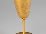 an antique gold goblet with a floral design on the stem