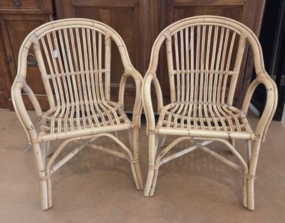 pair of white wicker chairs in front of a wooden door