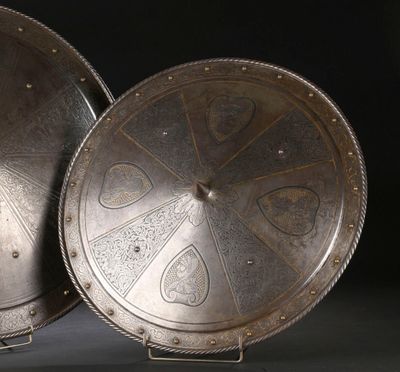 une paire de boucliers plaqués argent sur un socle, sur fond noir