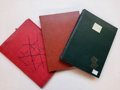 trois livres rouges et noirs posés sur une table blanche