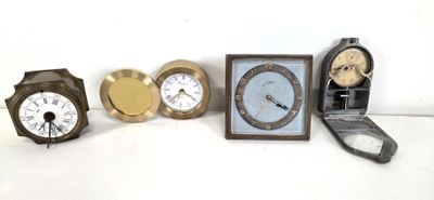four different clocks sitting next to each other on a white surface