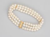 un gros plan sur un bracelet de perles blanches orné d'une breloque en forme d'étoile de mer en or