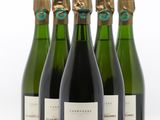 quatre bouteilles de vin sont alignées sur une surface blanche