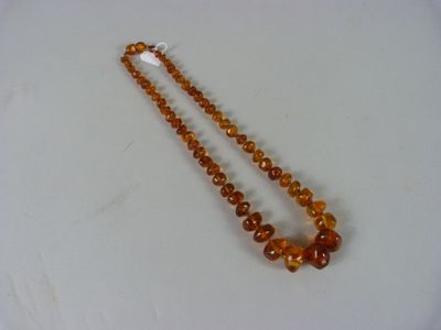 collier composé de perles d'ambre sur une surface blanche, avec un fond blanc