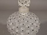 an image of a white glass perfume bottle with black dots