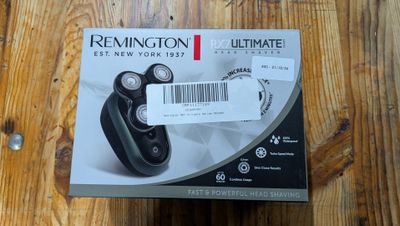 La boîte du rasoir Remington Ultimate est posée, ouverte, sur une table en bois.
