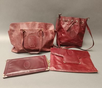 three red leather purses and a wallet sitting on a table