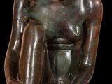 statue of a woman sitting on a stool with her hands on her knees