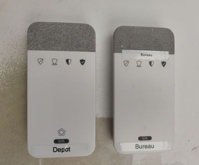 deux appareils connectés, l'un blanc et l'autre gris, posés sur un plan de travail