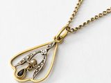 a close up of a gold and diamond necklace on a white surface