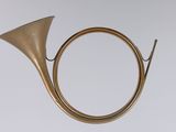 an old brass french horn on a stand against a white background