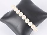 a close up of a white pearl bracelet on a black pillow