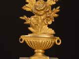 an image of a gold vase with flowers on a marble base