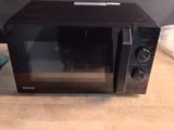 a black microwave sitting on a wooden table in the kitchen