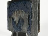 a black and blue vase with two legs on a white surface