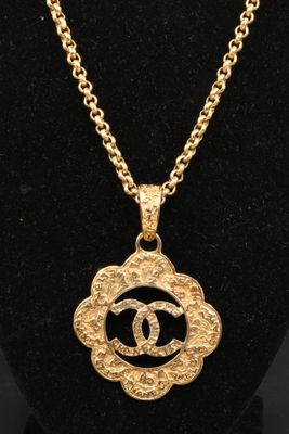 un collier en or orné d'une fleur et d'une chaîne, porté par un mannequin