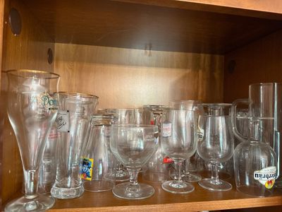 a wooden shelf filled with many glasses and vases