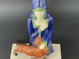 a figurine of a man with a bird on a stand