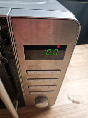 a clock on the side of a microwave on a wooden table