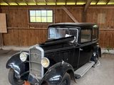 une vieille voiture noire dans un garage aux murs en bois
