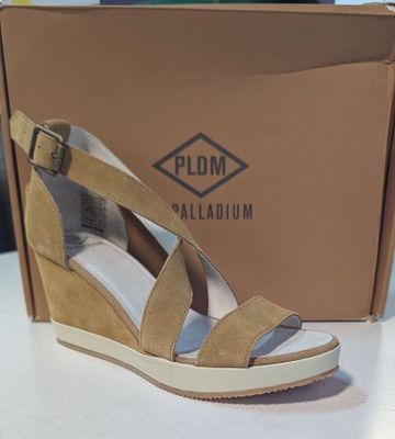 La femme porte une paire de sandales à talons compensés devant un carton.