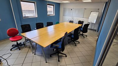 une longue table au milieu d'une pièce, entourée de chaises