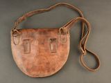 a brown leather purse with a strap on a gray surface