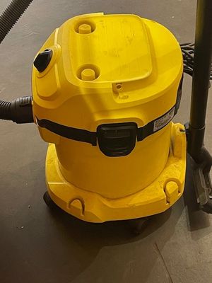 un aspirateur jaune posé par terre à côté d'un poteau